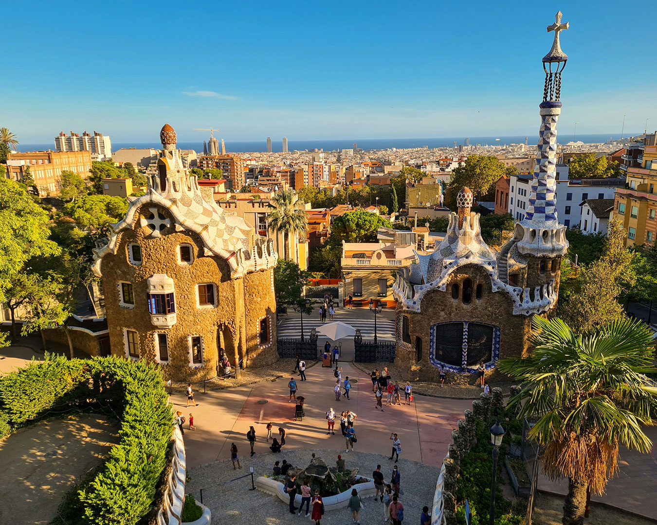 Eingang des Park Güell mit Gaudís Häusern und Blick über Barcelona zum Mittelmeer