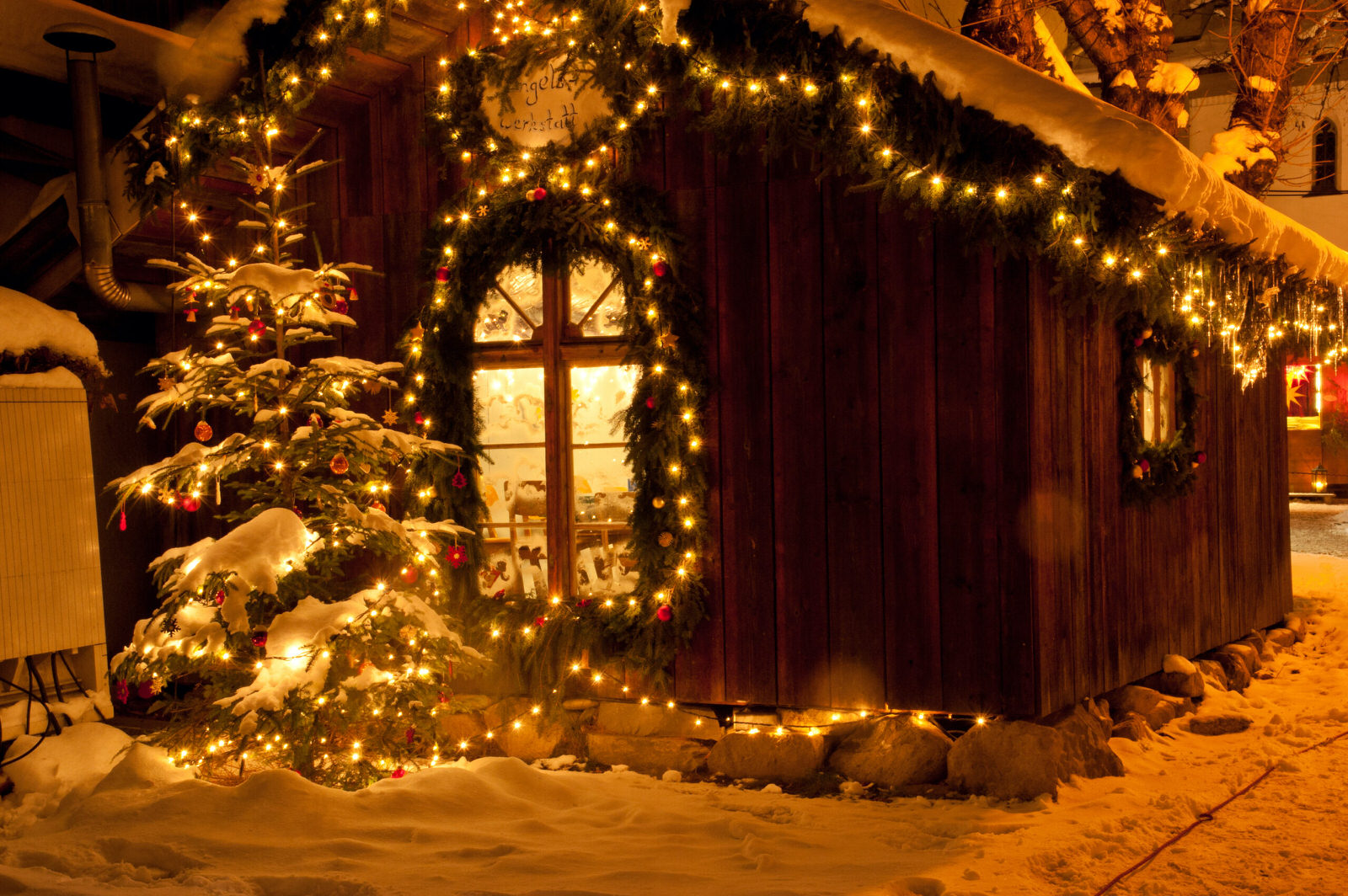 Festlich geschmückte Holzhütte mit Tannenbaum und Lichterketten beim Bad Hindelang Weihnachtsmarkt – romantische Winteridylle