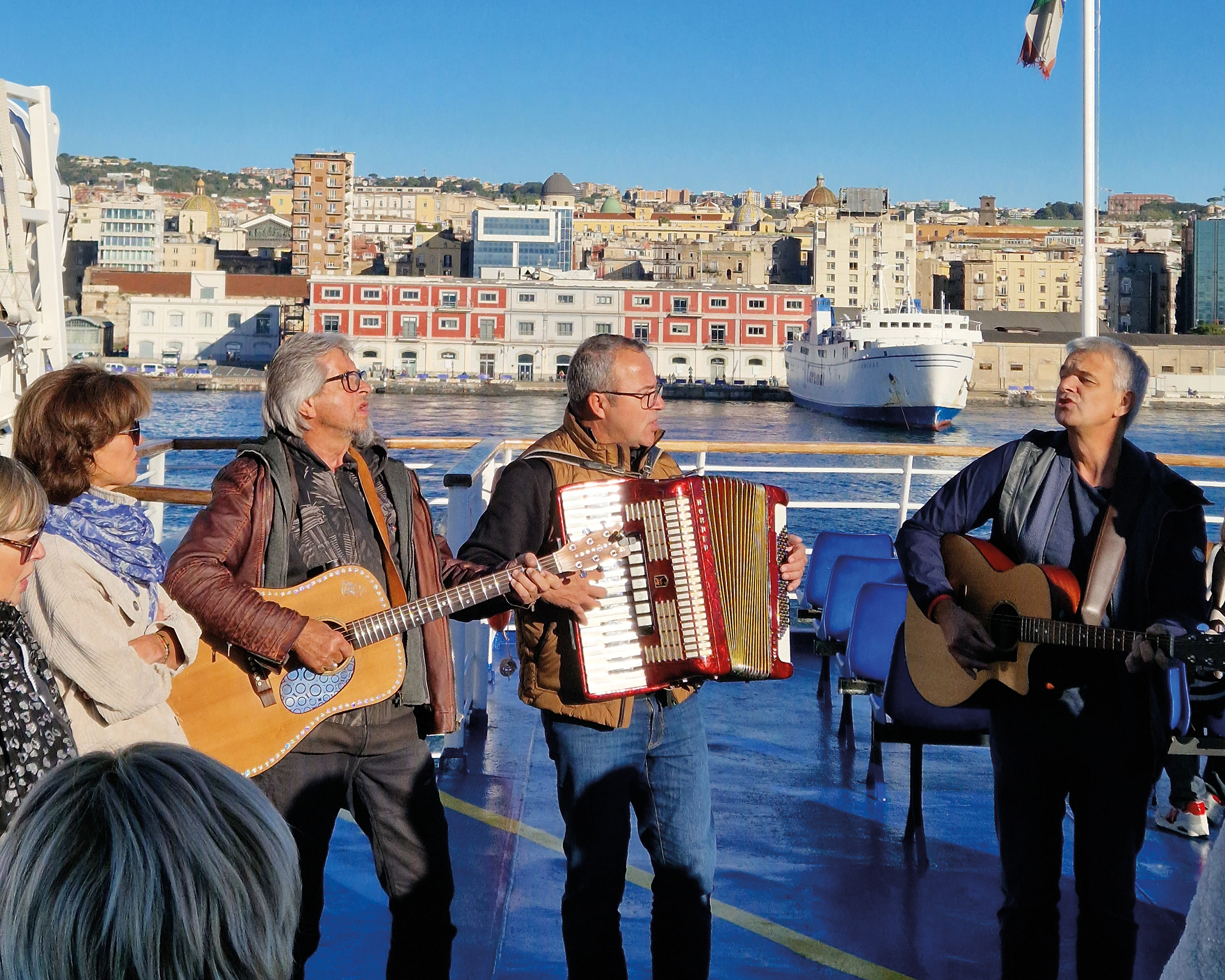 Musikgruppe „Habe die Ehre“ mit Gitarre und Akkordeon auf einer Fähre vor der italienischen Küste – stimmungsvolle Unterhaltung bei einer RiGel Reise.