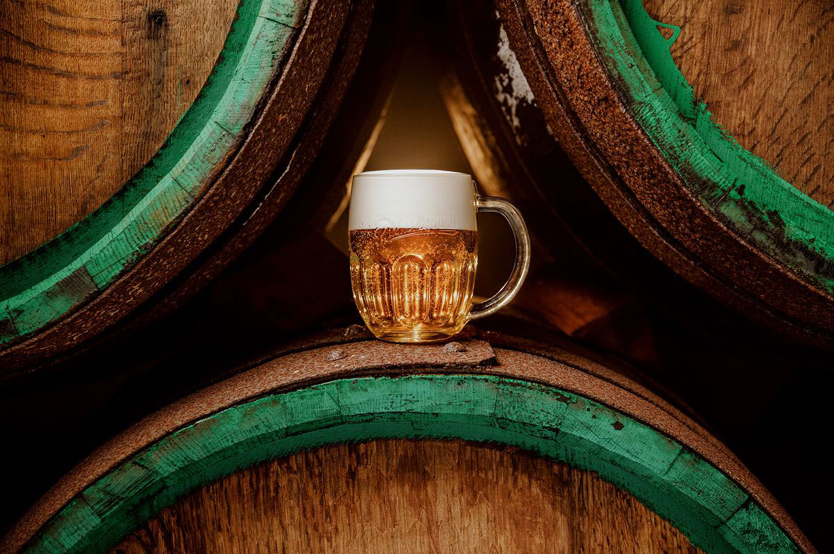 Frisch gezapftes Pilsner Bier zwischen traditionellen Holzfässern