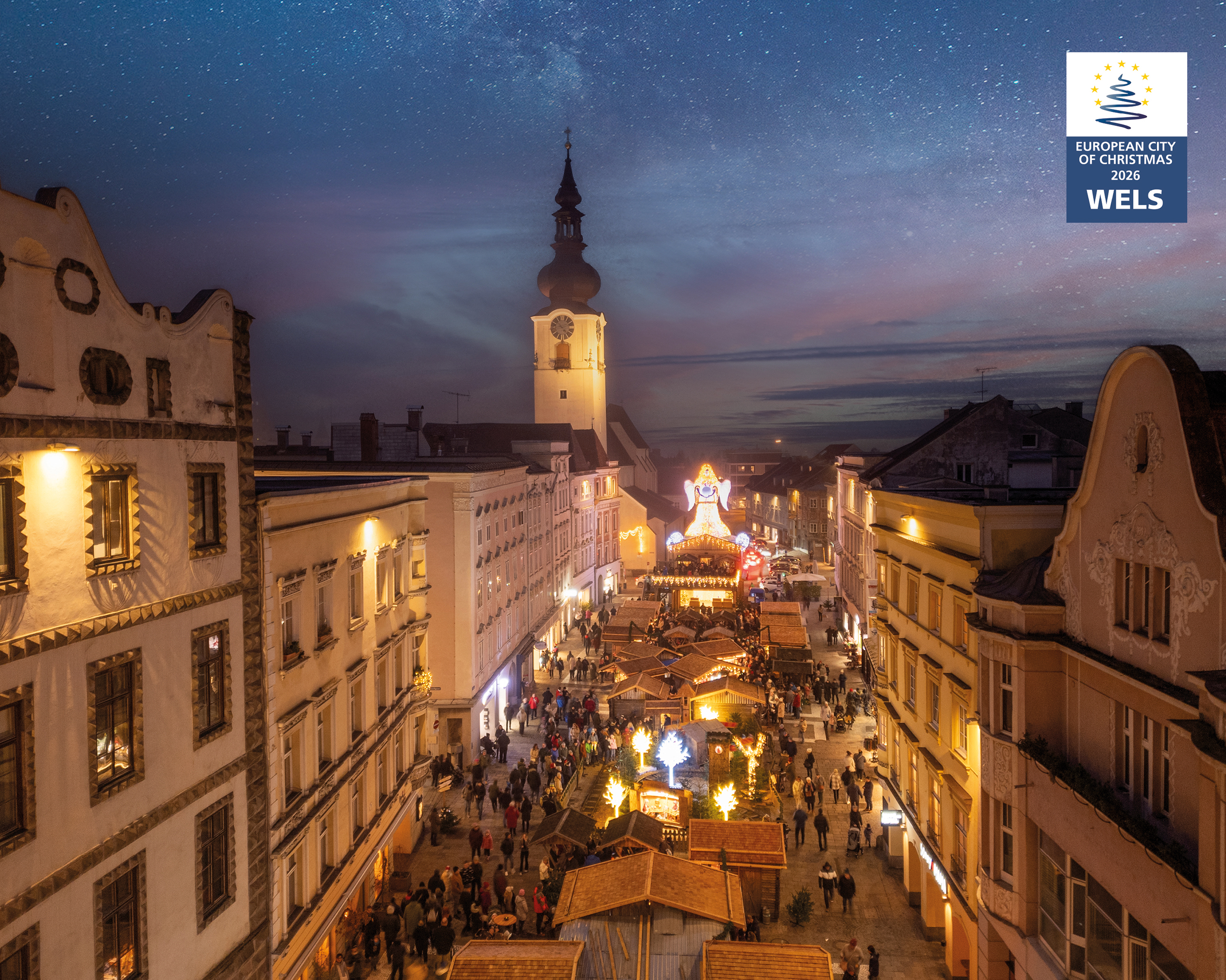 Blick über den Weihnachtsmarkt in Wels mit beleuchteten Hütten und historischer Altstadt bei Nacht – © Tourismusverband Region Wels / Peter Echt