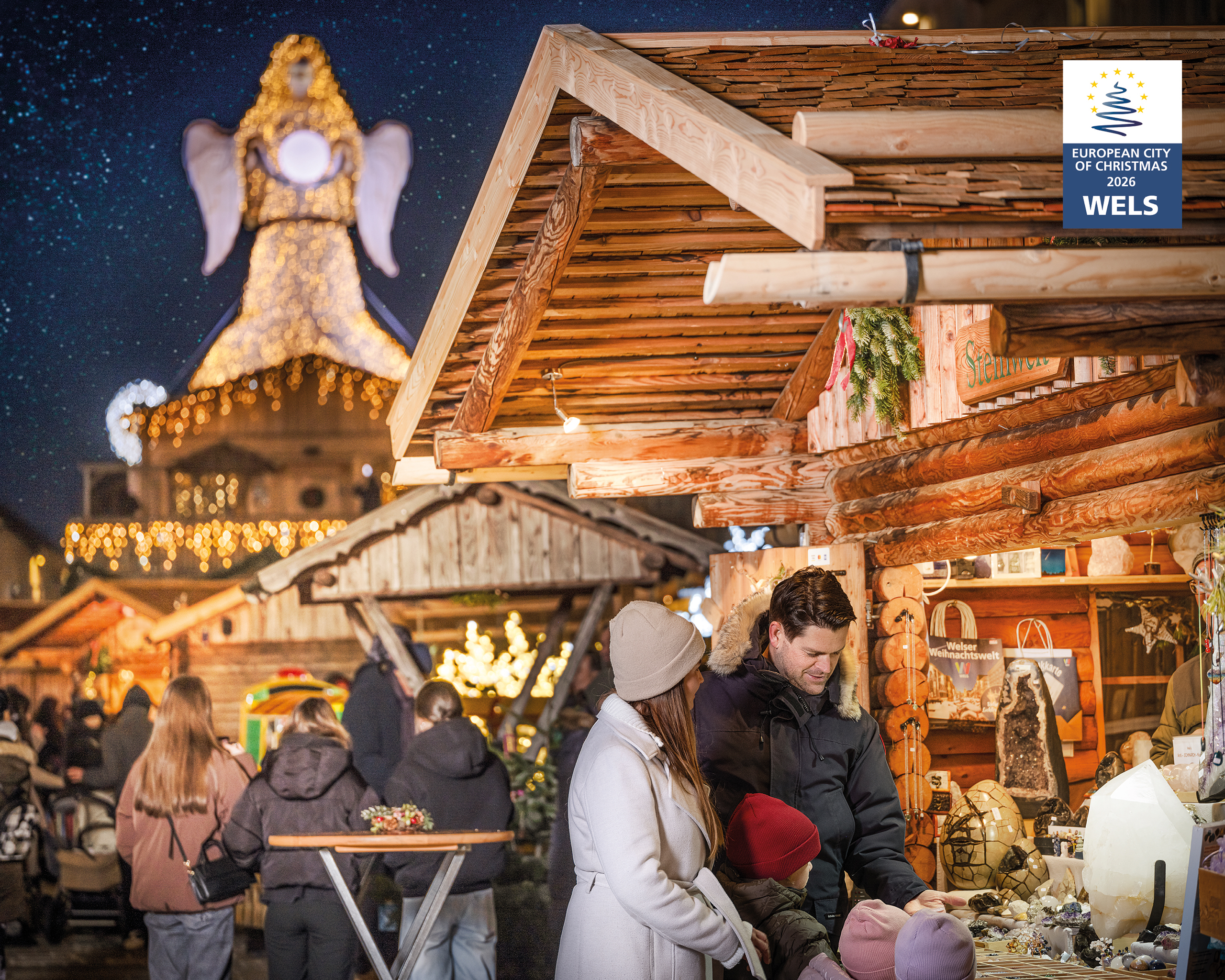Adventmarkt in Wels bei Nacht mit stimmungsvoll beleuchteten Holzhütten und Besuchern beim Bummeln, festliche Weihnachtsbeleuchtung in Oberösterreich – © Tourismusverband Region Wels