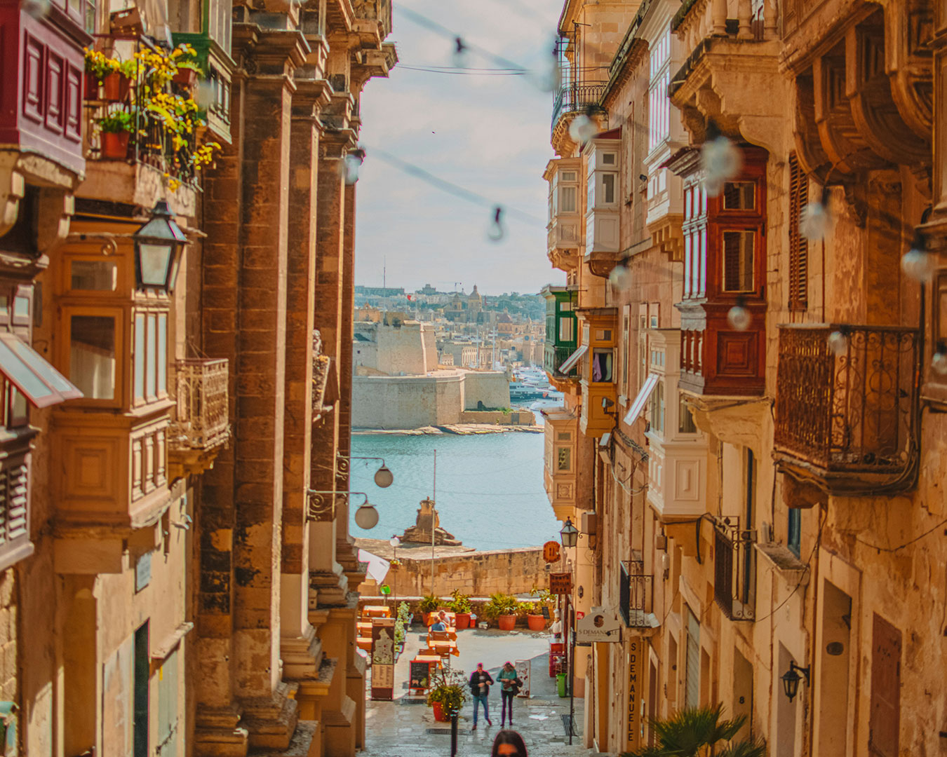 Historische Gasse in Valletta mit traditionellen maltesischen Holzbalkonen und Blick auf den Hafen