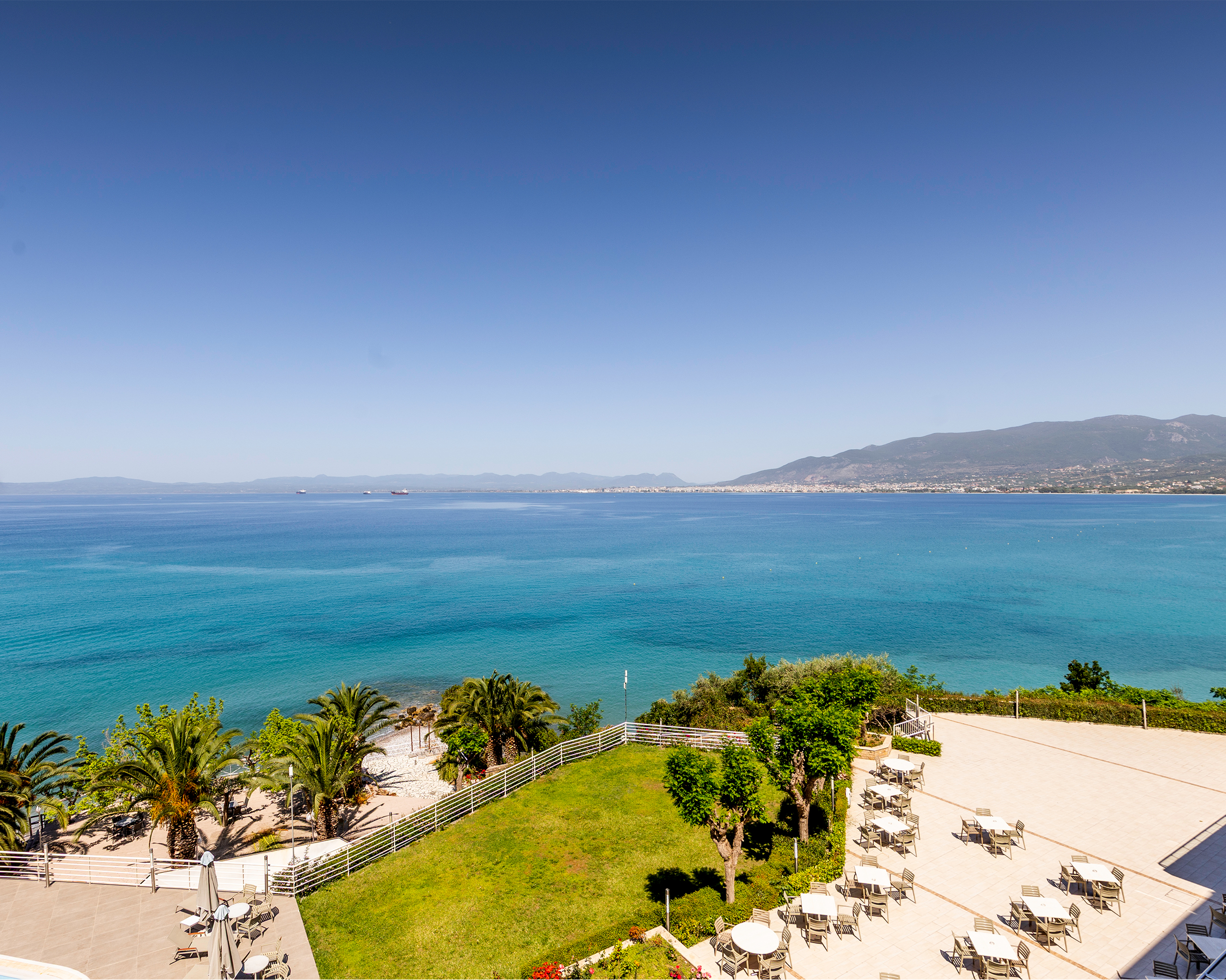Panoramablick über das türkisfarbene Meer bei Kalamata mit Palmen, Hotelterrasse und Küstenlinie im Hintergrund, Messinian Bay, Griechenland. © Idealtours