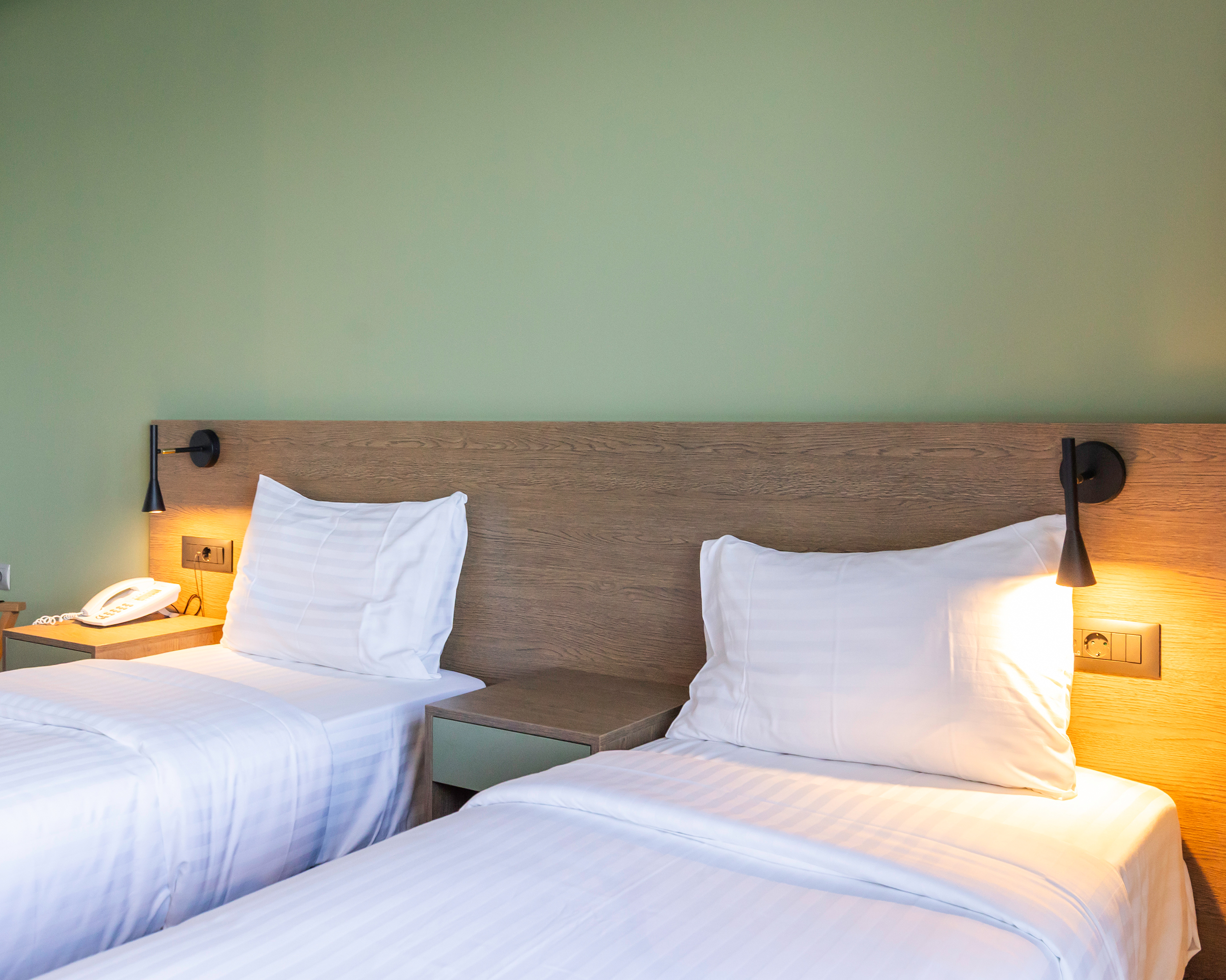 Helles Hotelzimmer mit zwei getrennten Betten, moderner Einrichtung und warmem Licht im Messinian Bay Hotel, Kalamata. © Idealtours