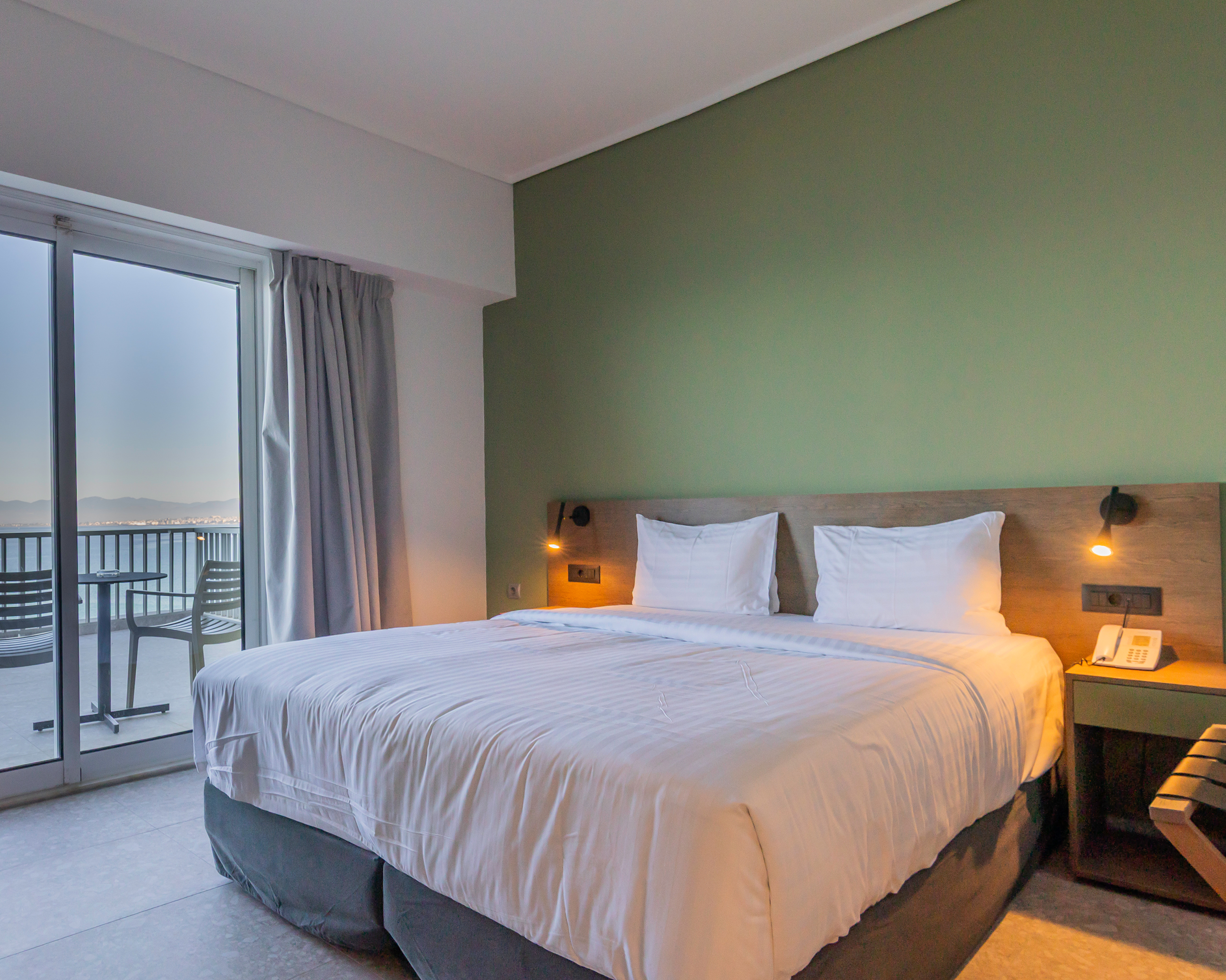 Modernes Hotelzimmer mit Doppelbett und Balkon mit Meerblick im Messinian Bay Hotel bei Kalamata, Griechenland. © Idealtours