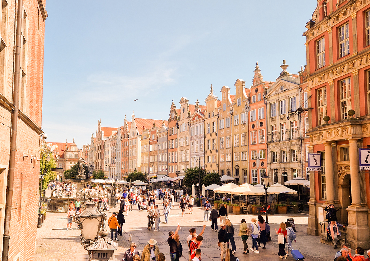 Blick auf den Langen Markt in Danzig mit bunten historischen Bürgerhäusern und zahlreichen Besuchern.