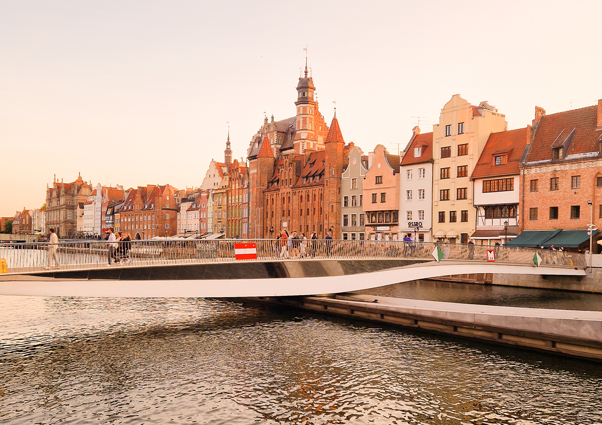 Abendstimmung an der Mottlau mit moderner Fußgängerbrücke und historischen Häuserfassaden in Danzig.