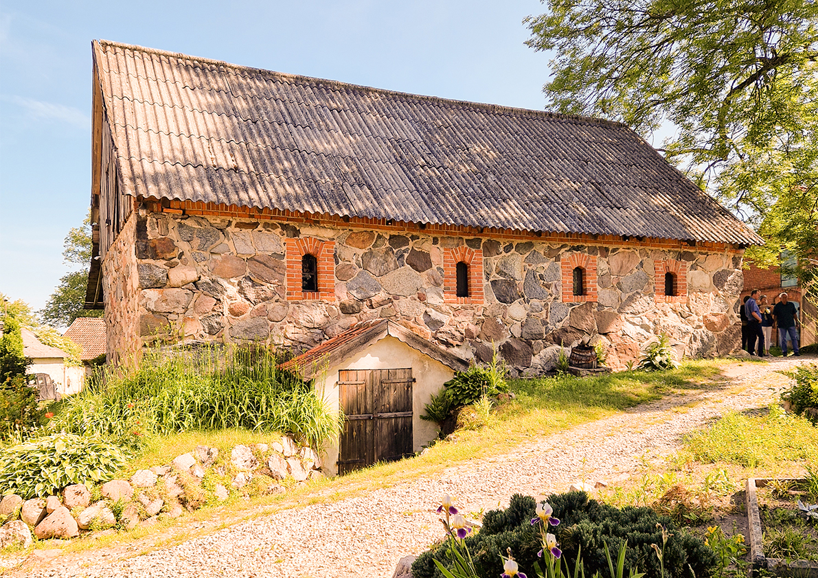 Altes Steinhaus mit Ziegeldach in idyllischer ländlicher Umgebung in Polen.