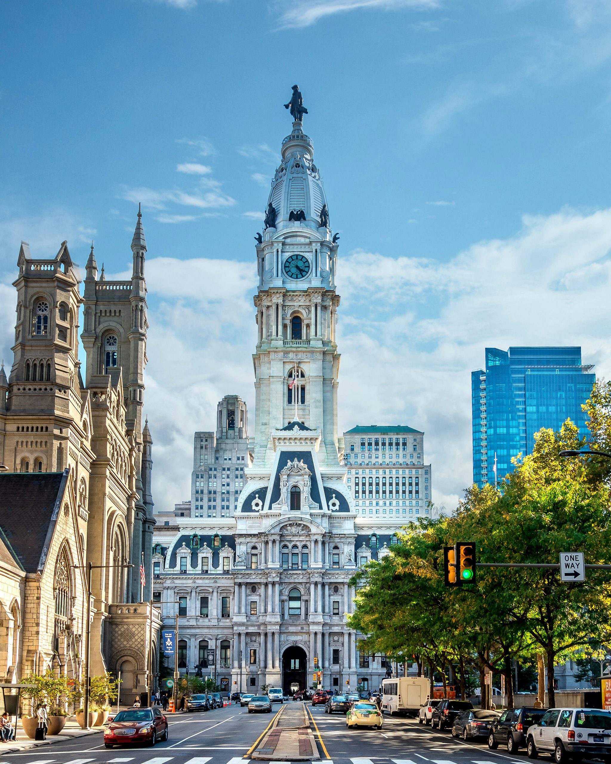 Die historische City Hall von Philadelphia mit markantem Uhrturm, umgeben von moderner Architektur und belebter Straße.