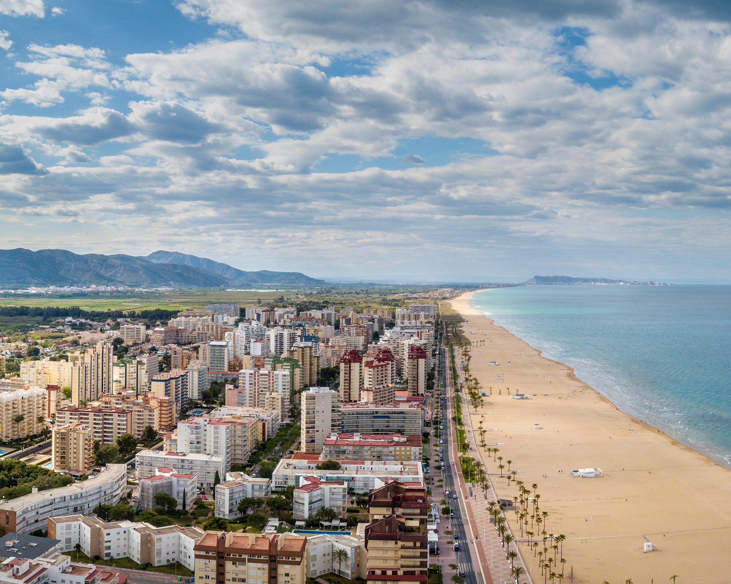 Panoramablick auf Gandia mit breitem Sandstrand, Promenade und türkisblauem Meer – mediterranes Urlaubsgefühl pur.