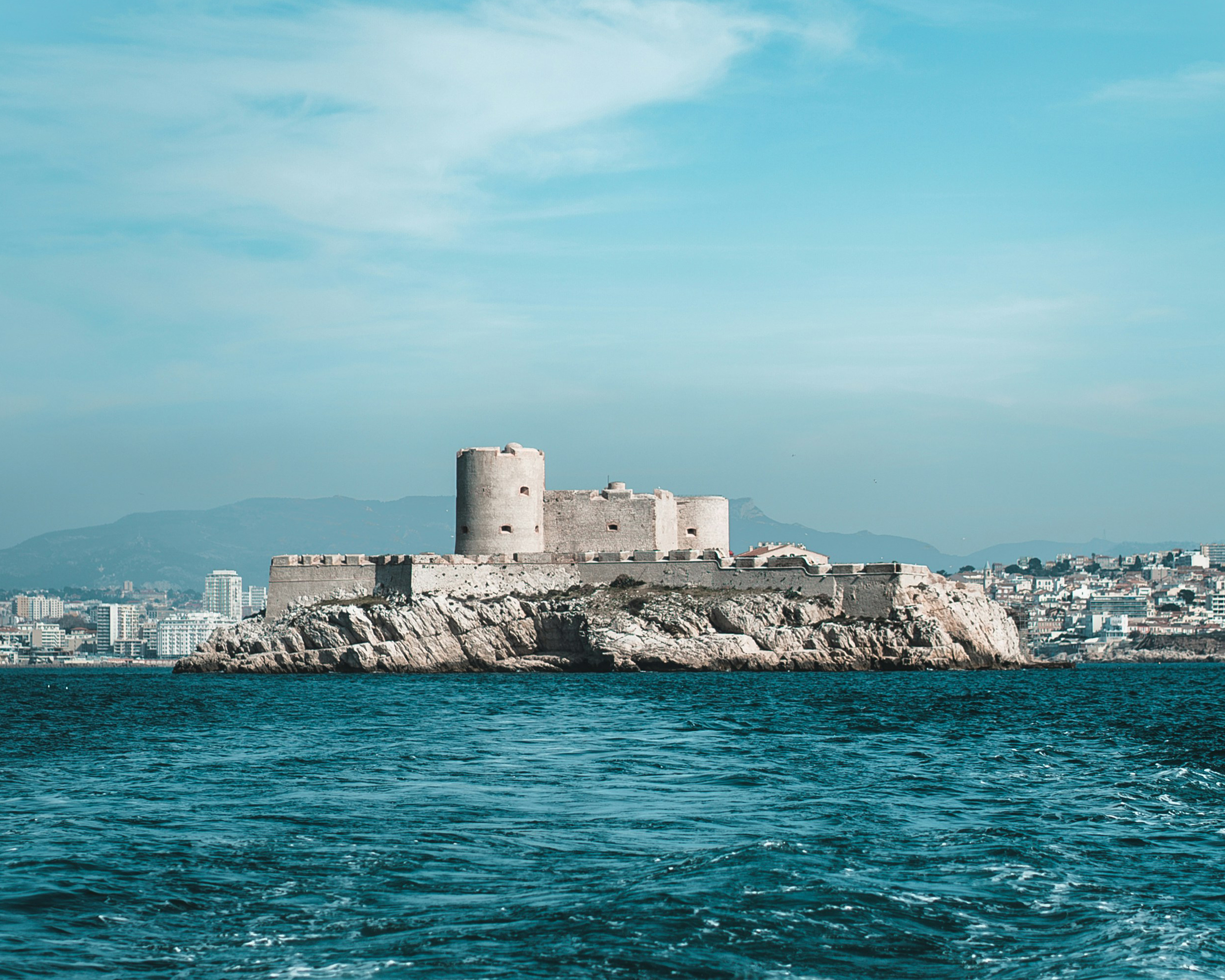 Steinerne Festung Château d’If auf einer kleinen Insel vor der Küste von Marseille, umgeben vom tiefblauen Mittelmeer unter klarem Himmel.
