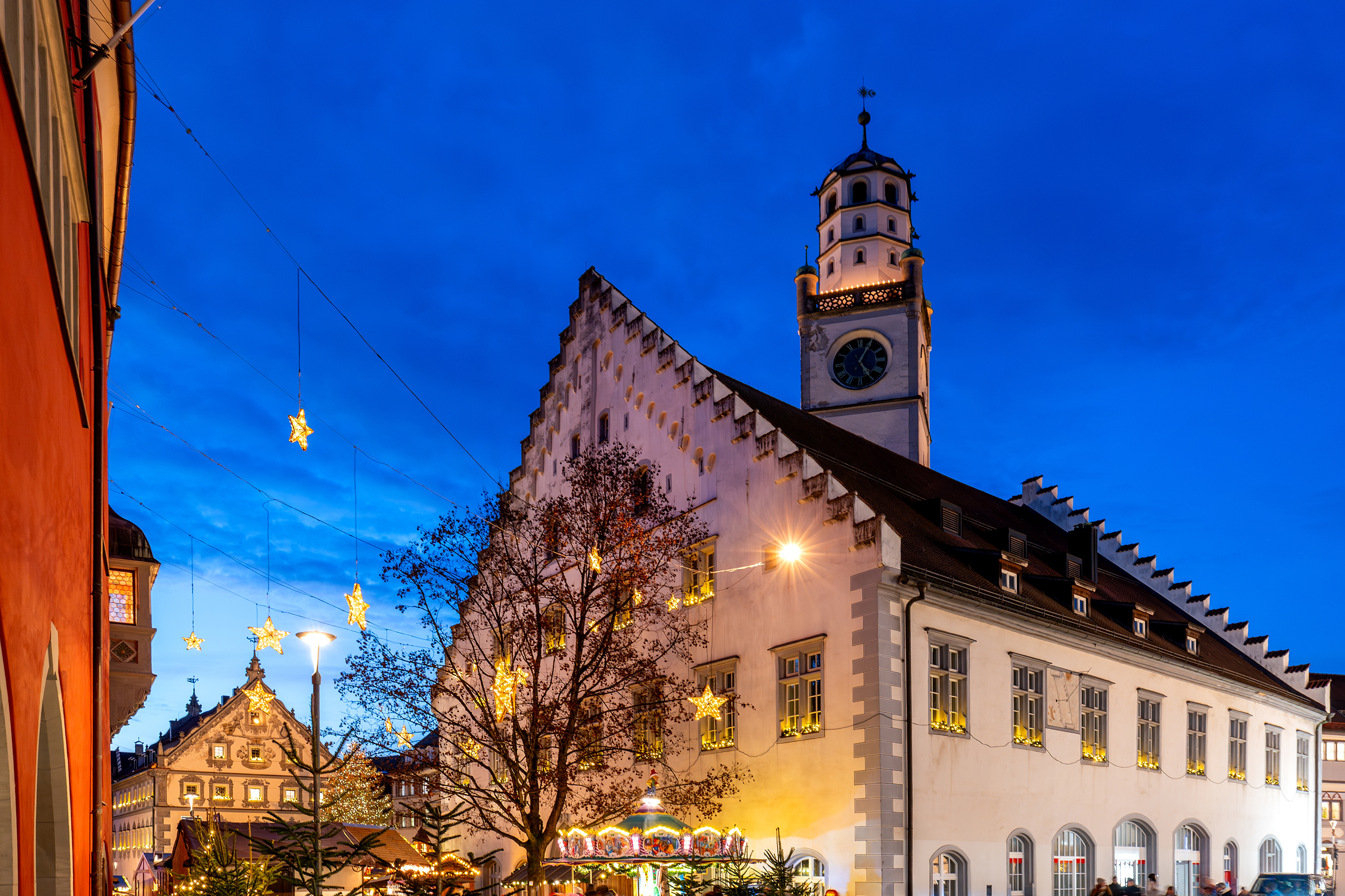 Romantischer Weihnachtsmarkt in Ravensburg mit festlich beleuchtetem historischem Rathaus unter tiefblauem Abendhimmel