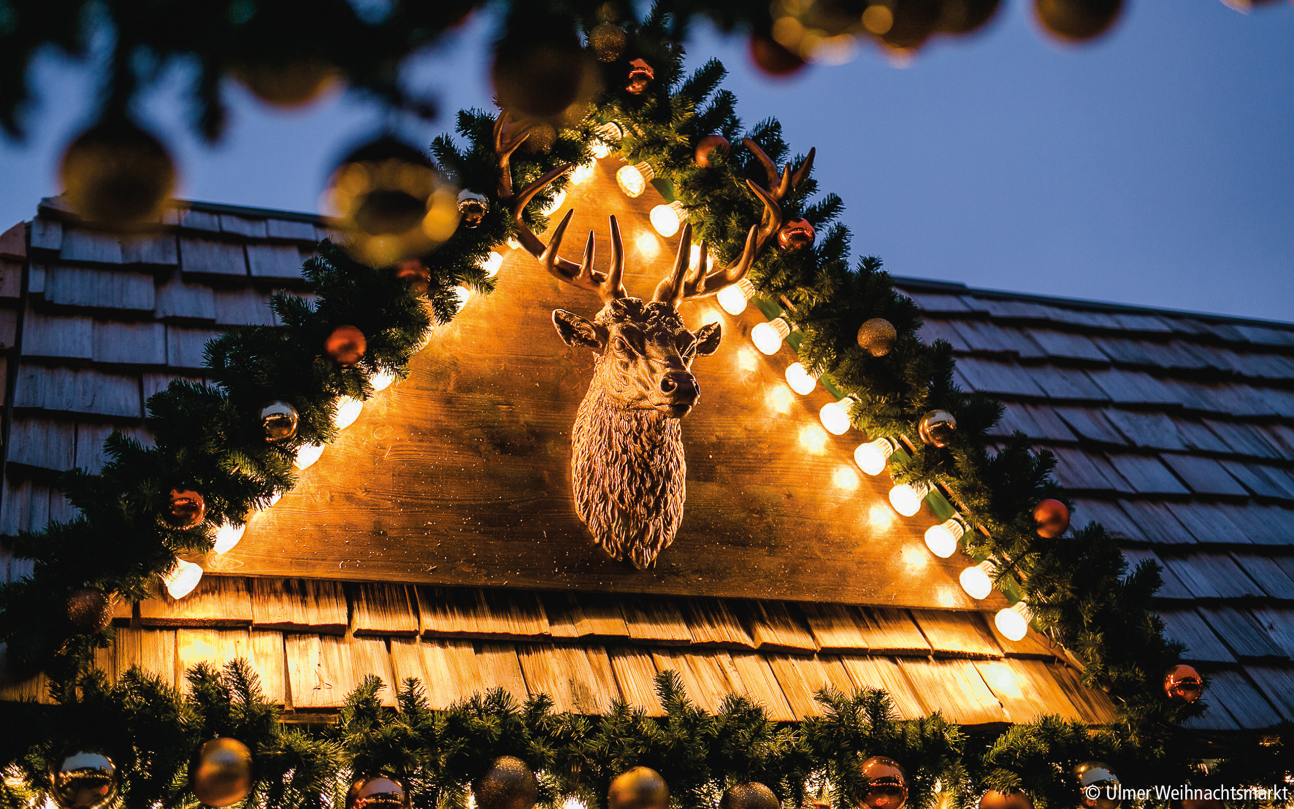 Festlich geschmückte Holzhütte mit beleuchtetem Hirschkopf – urige Atmosphäre auf dem Ulmer Weihnachtsmarkt