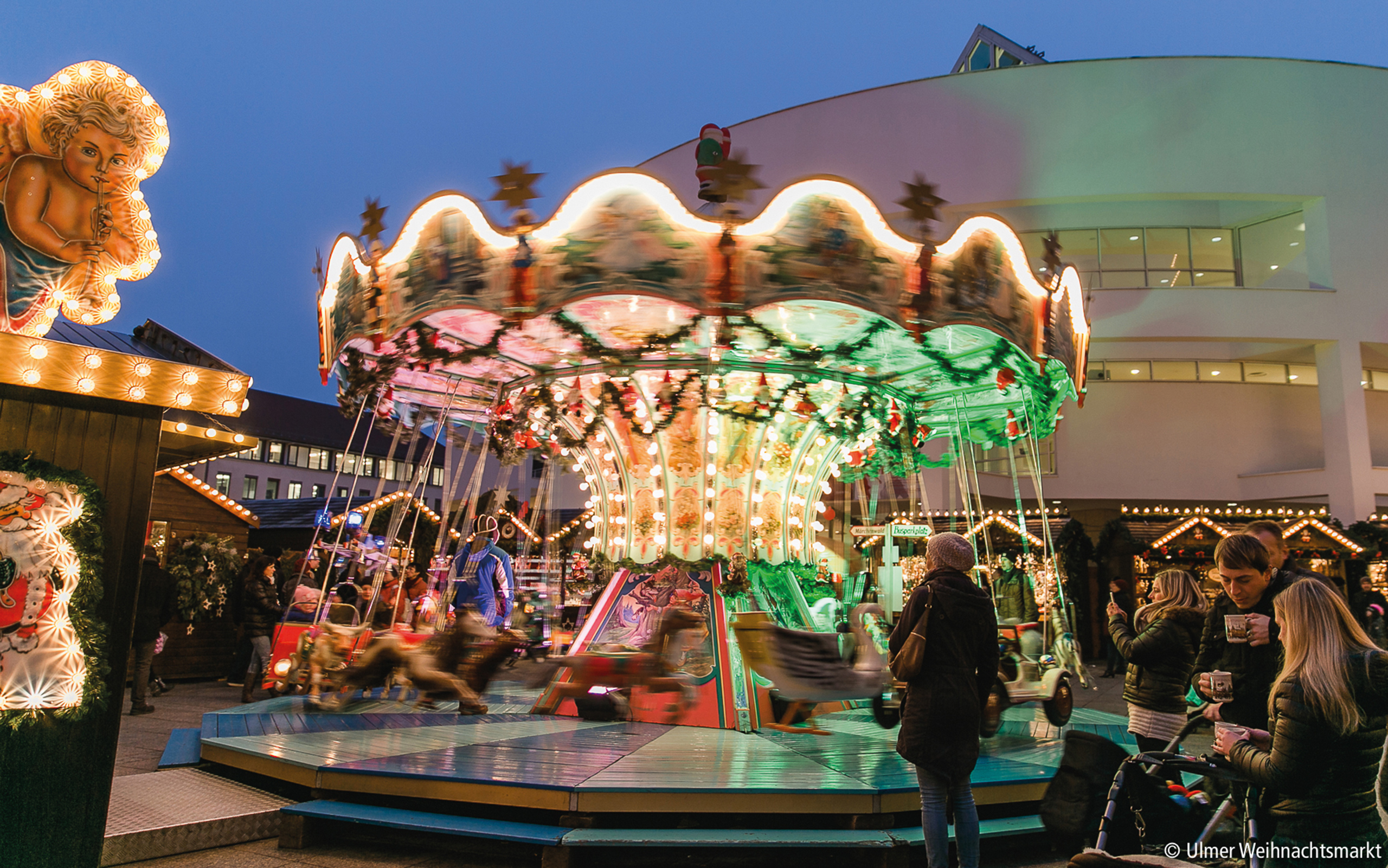 Bunt beleuchtetes Karussell auf dem Ulmer Weihnachtsmarkt bei Abendstimmung – festliche Atmosphäre für die ganze Familie