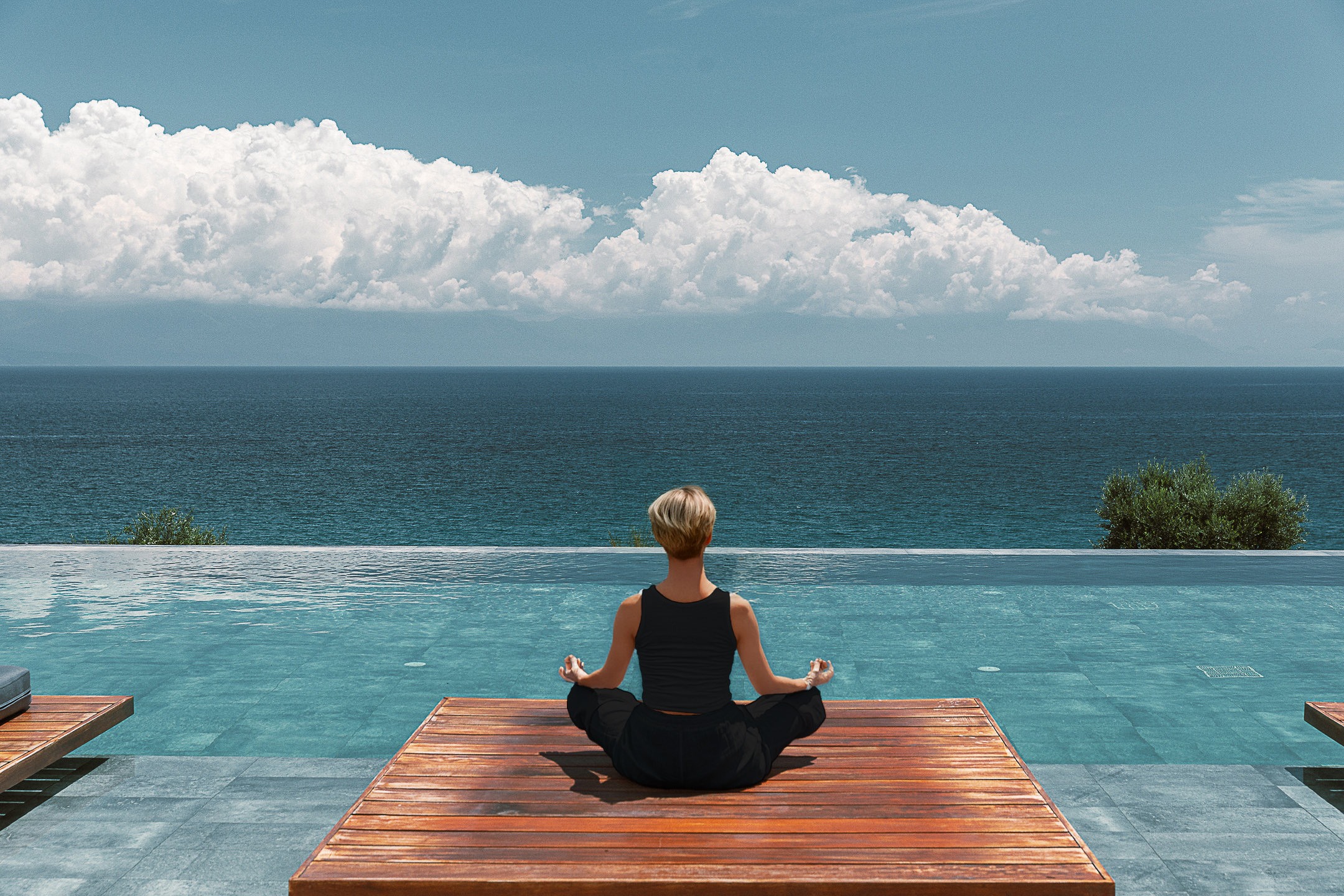 Yogalehrerin macht Yoga am Infinity Pool mit Blick aufs Meer in Griechenland – Ruhe und Entspannung im Urlaub