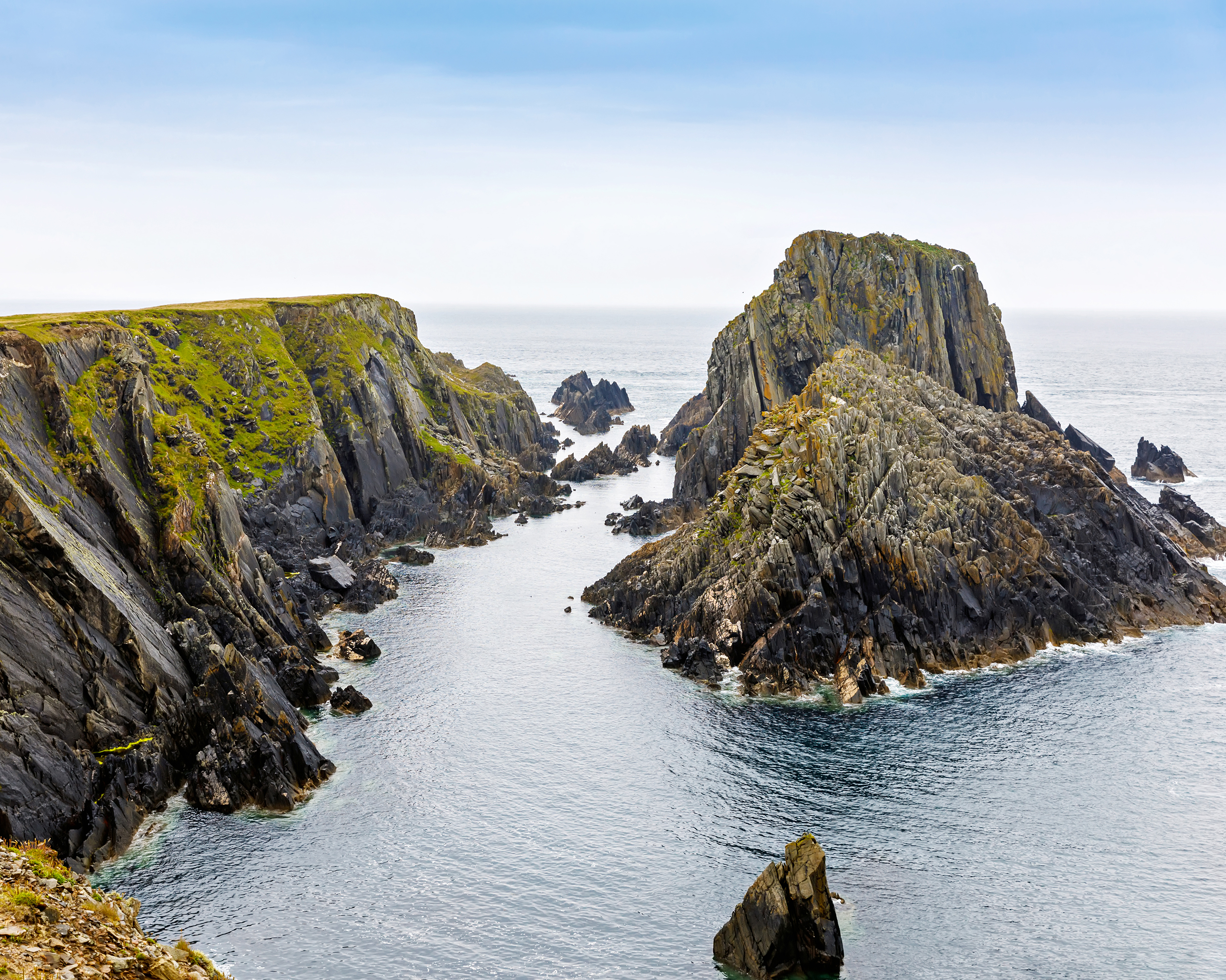 Zerklüftete Steilküste der Slieve League Cliffs im County Donegal in Irland mit schroffen Felsformationen, grünen Klippen und einer schmalen Meeresbucht am Atlantik.