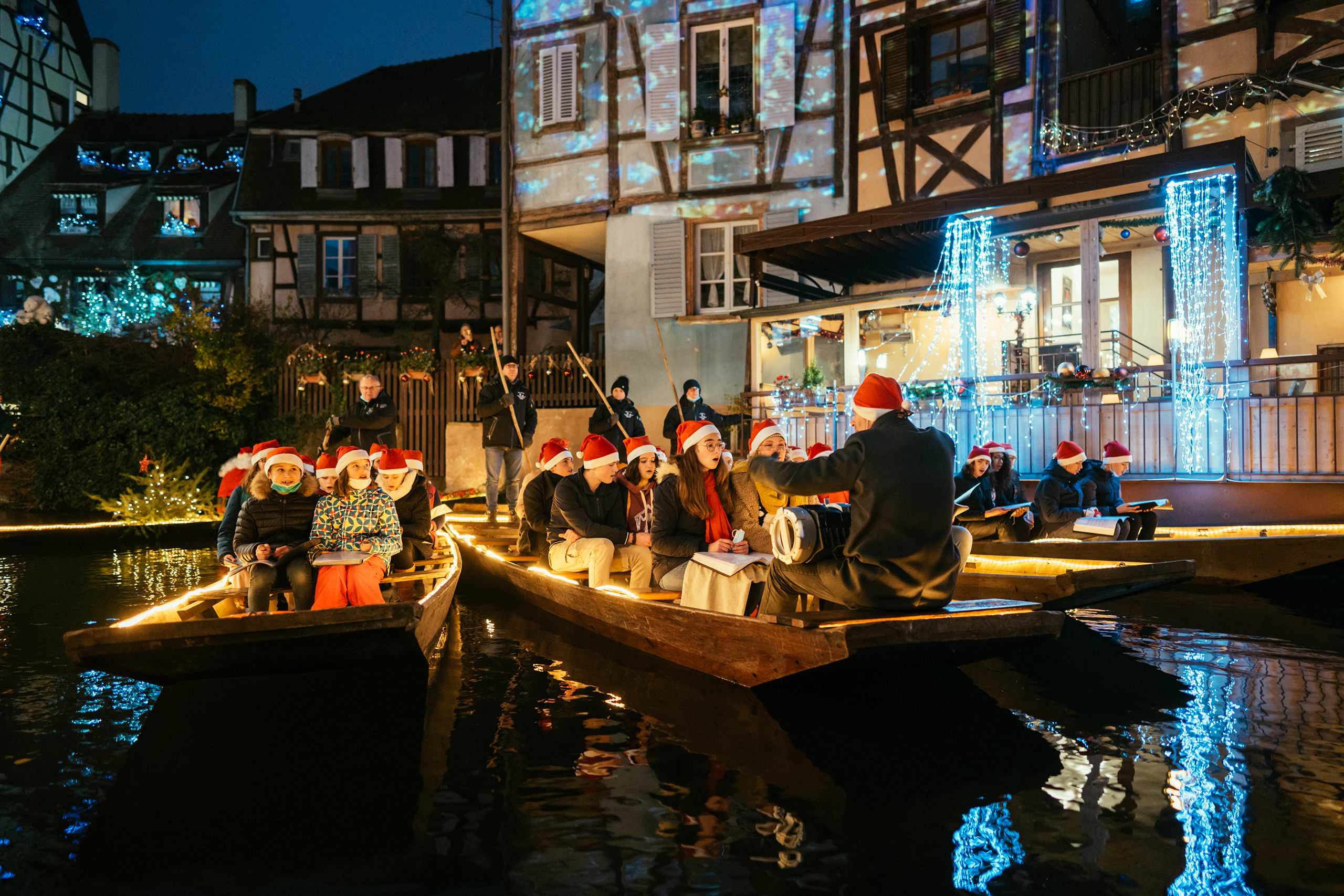 Weihnachtlich geschmückte Boote mit Chorsängern in roten Nikolausmützen gleiten durch Colmars romantische Kanäle, begleitet von festlicher Beleuchtung.
