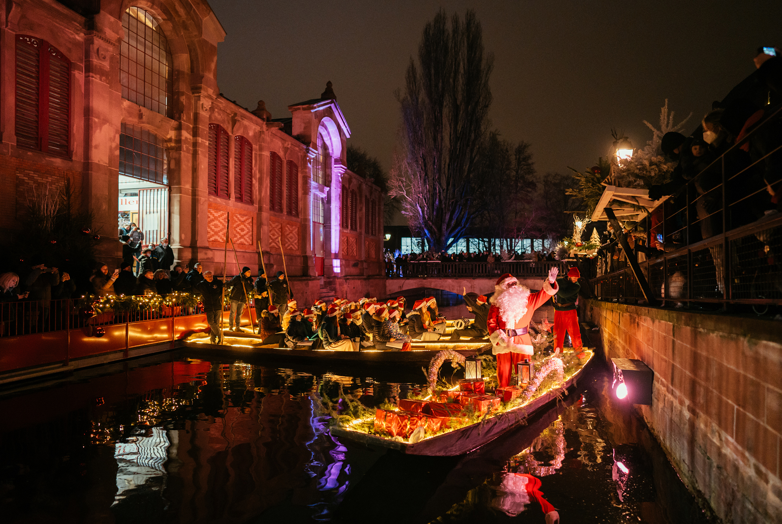„Der Weihnachtsmann begrüßt die Besucher von einem festlich dekorierten Boot, während Chöre in Colmars Kanälen Weihnachtslieder singen