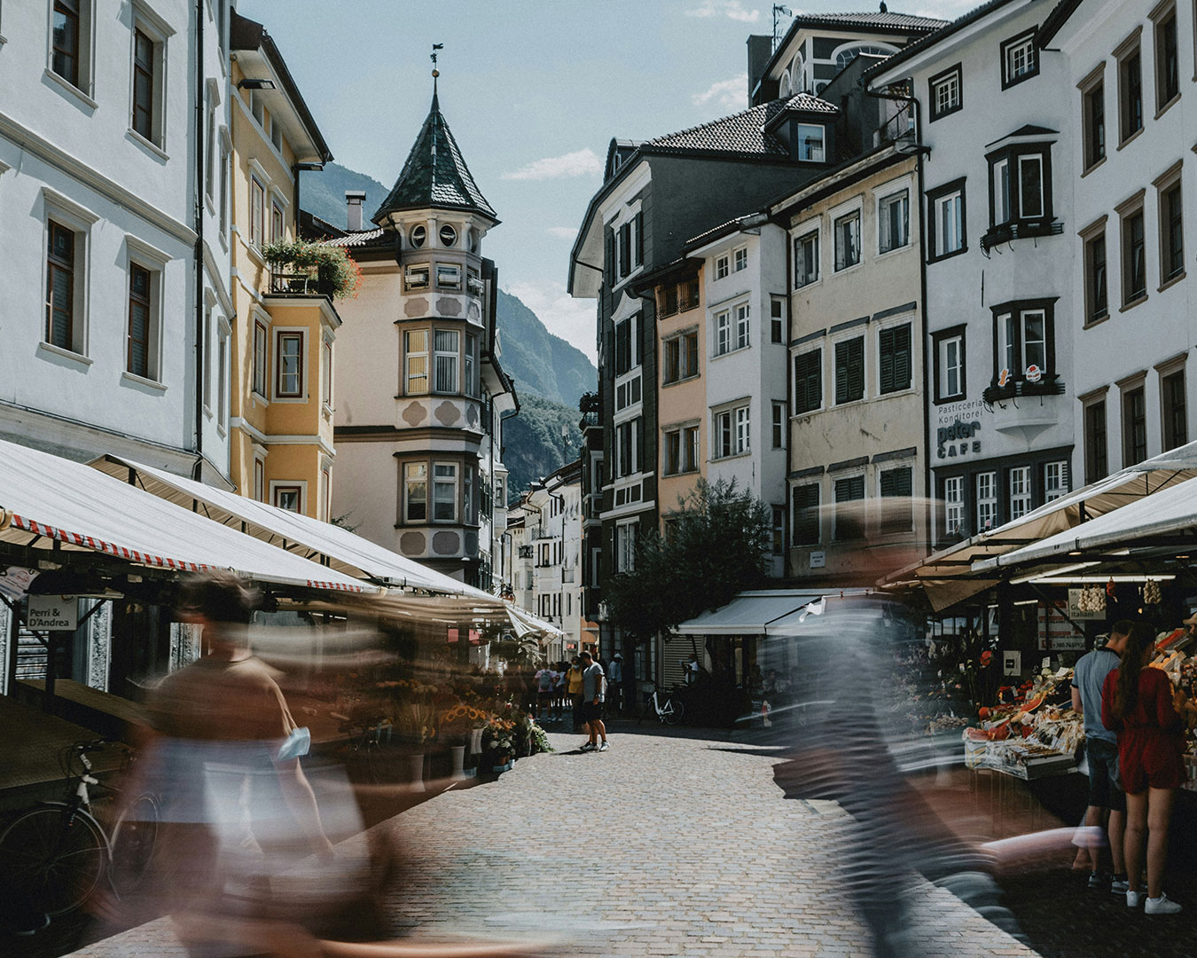 Historische Altstadtgasse in Bozen mit Marktständen, traditionellen Häusern und Passanten