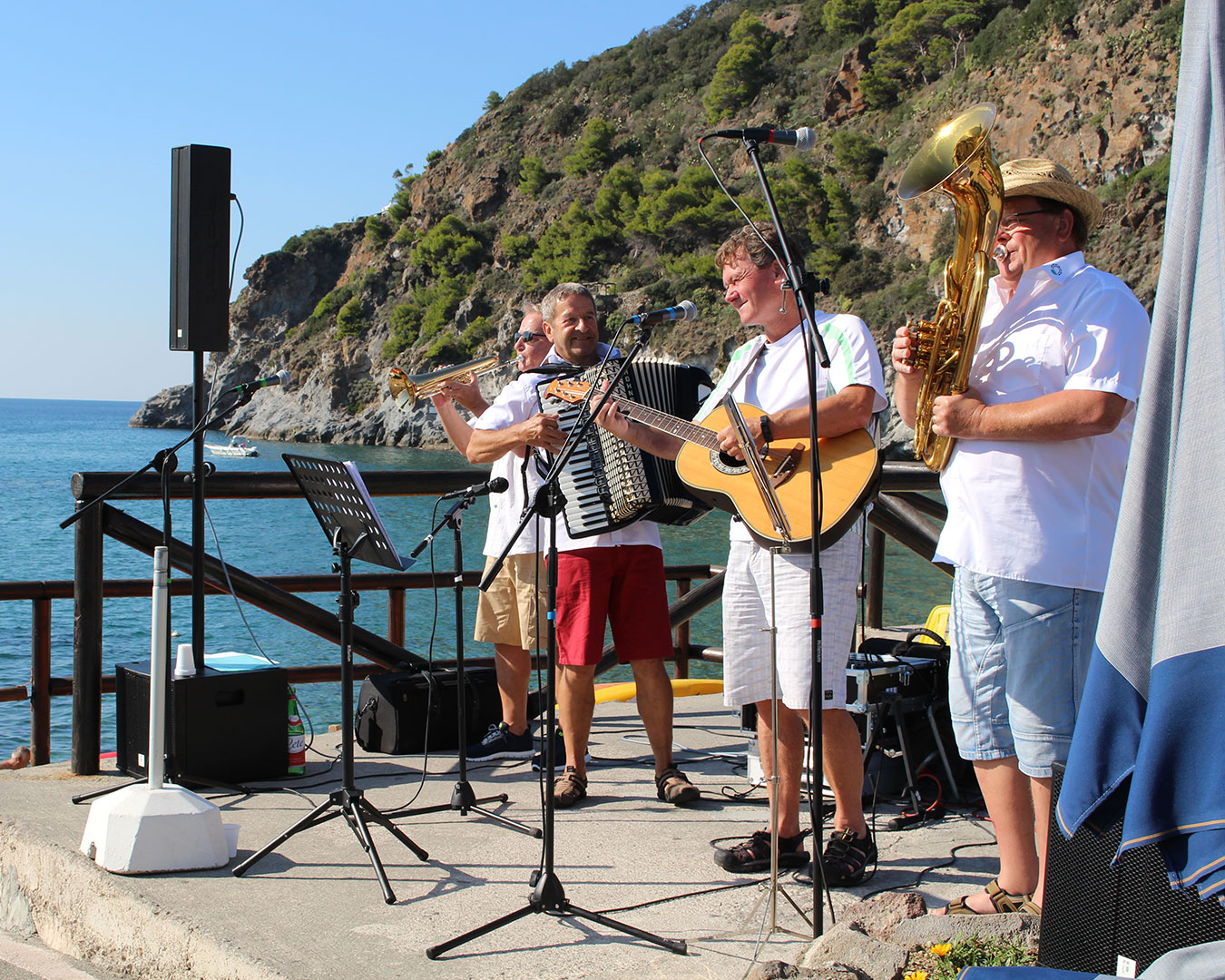 Die Stegreiffler spielen mit Trompete, Akkordeon, Gitarre und Tuba am Meer auf Ischia