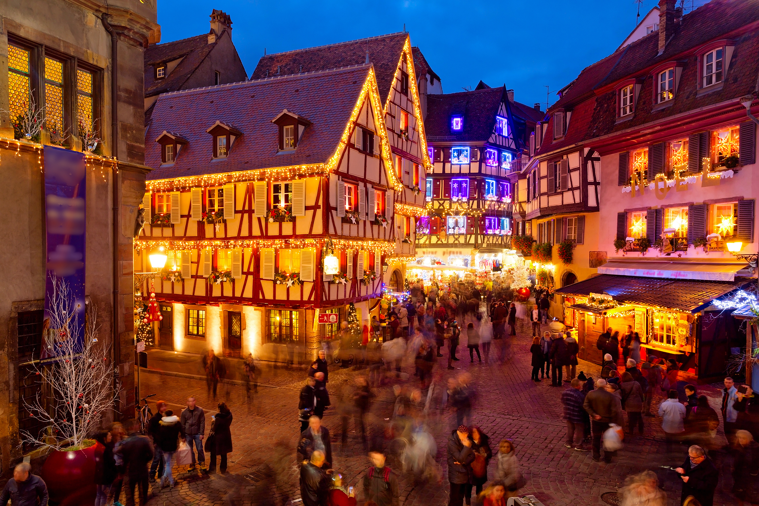 Lichterketten und geschmückte Fachwerkhäuser tauchen Colmars Altstadt in ein märchenhaftes Leuchten beim Weihnachtsmarkt am Abend