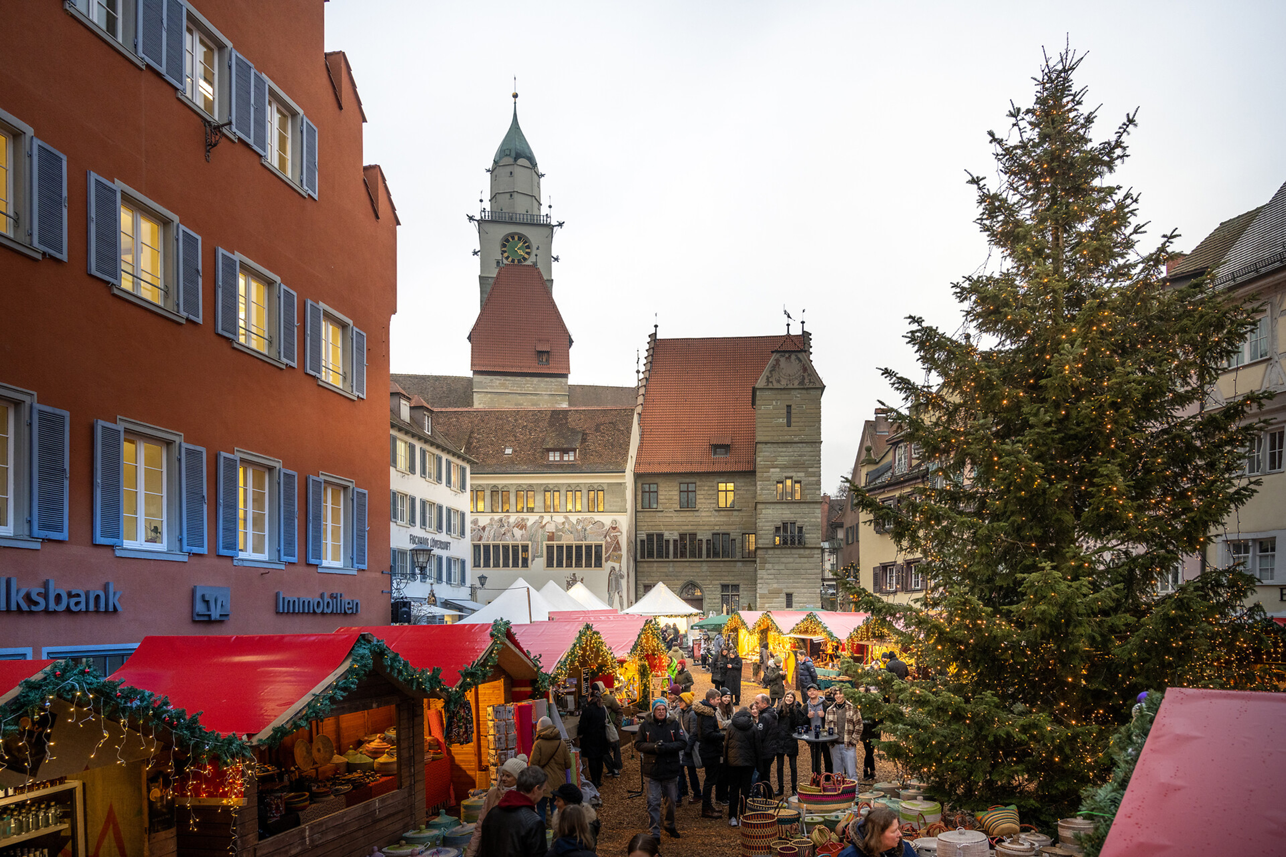 Weihnachtsmarkt in Überlingen mit bunten Ständen, geschmücktem Weihnachtsbaum und dem markanten Stadtturm im Hintergrund