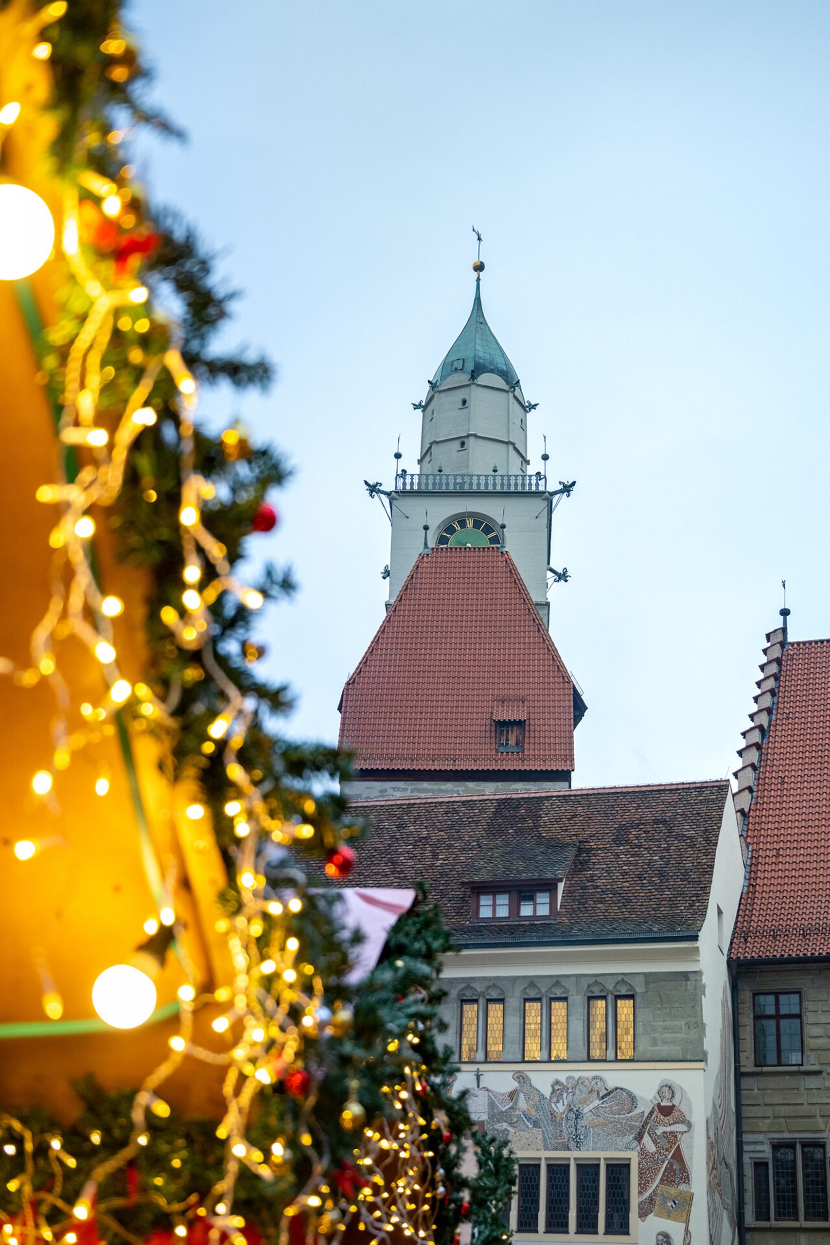 Blick auf den historischen Turm von Überlingen, eingerahmt von festlich beleuchteten Girlanden des Weihnachtsmarktes